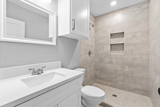 bathroom with vanity, toilet, and tiled shower