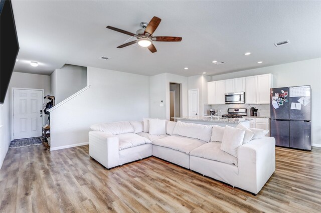 living room featuring ceiling fan and light hardwood / wood-style floors