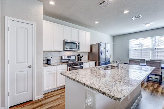 kitchen featuring appliances with stainless steel finishes, a kitchen island with sink, sink, and white cabinets