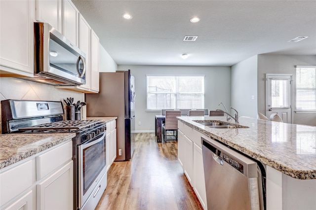 kitchen featuring stainless steel appliances, white cabinetry, sink, and a kitchen island with sink