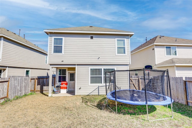 back of property featuring a trampoline and a lawn