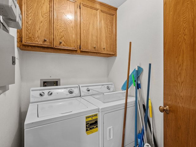 clothes washing area with cabinets and washer and clothes dryer