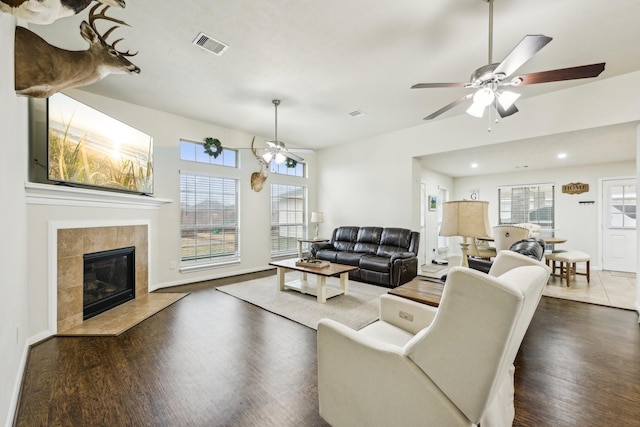 living room featuring a tiled fireplace, dark hardwood / wood-style floors, and ceiling fan