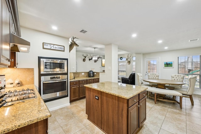 kitchen featuring appliances with stainless steel finishes, a center island, and light stone countertops