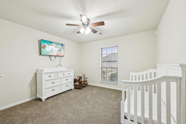 bedroom featuring a nursery area, ceiling fan, and light carpet