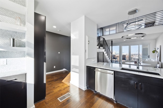 kitchen featuring sink, hanging light fixtures, stainless steel dishwasher, light stone counters, and dark wood-type flooring