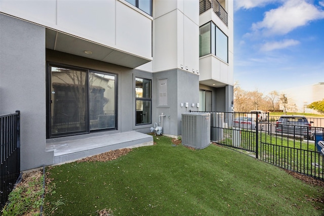 exterior space featuring a yard, fence, central AC unit, and stucco siding