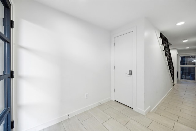 hallway featuring wood finish floors, stairway, recessed lighting, and baseboards