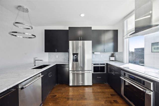 kitchen with wall chimney exhaust hood, sink, appliances with stainless steel finishes, dark hardwood / wood-style floors, and pendant lighting