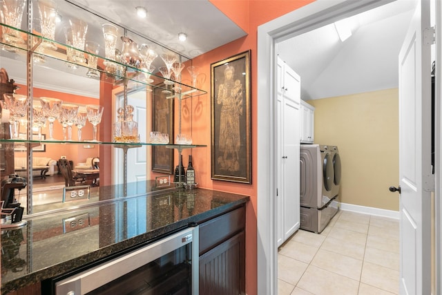 bar featuring light tile patterned flooring, dark stone countertops, white cabinets, beverage cooler, and washer and clothes dryer