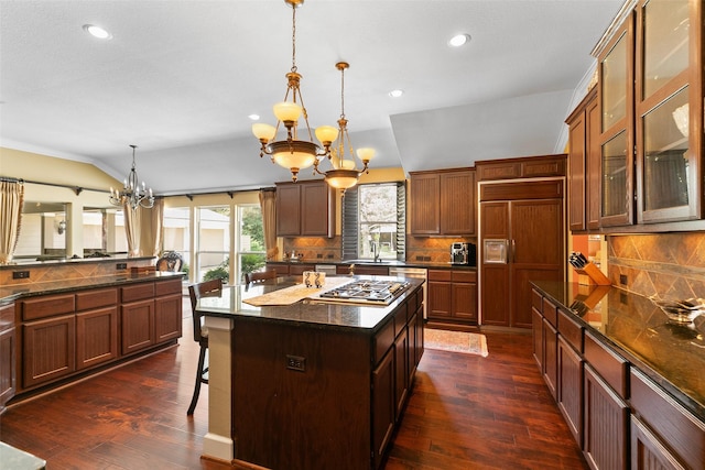 kitchen with a kitchen island, stainless steel gas stovetop, a breakfast bar area, hanging light fixtures, and paneled refrigerator