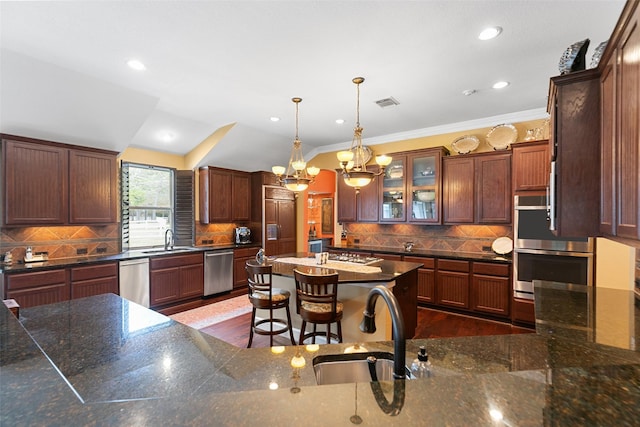 kitchen with pendant lighting, sink, a breakfast bar, dark stone countertops, and stainless steel appliances