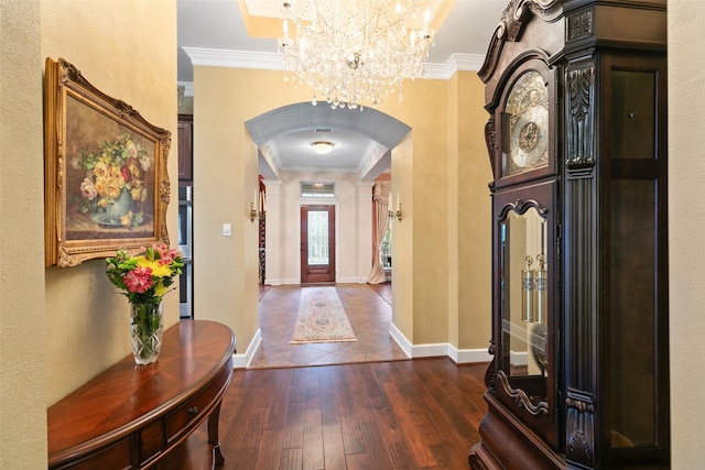 entryway with an inviting chandelier, dark wood-type flooring, and ornamental molding