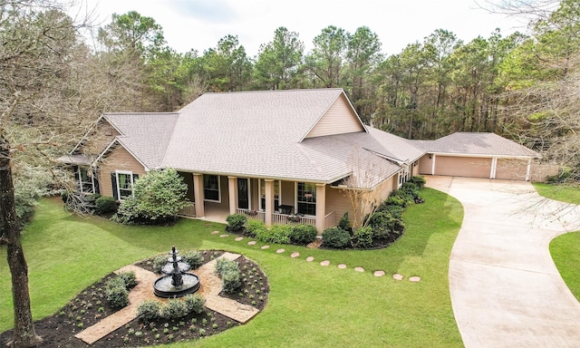 view of front of home featuring a garage, covered porch, and a front lawn