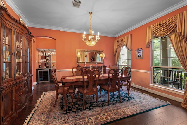 dining space featuring dark wood-type flooring, crown molding, a chandelier, and wine cooler