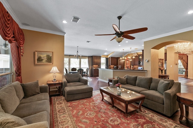 living room featuring crown molding, ceiling fan with notable chandelier, a textured ceiling, and hardwood / wood-style flooring