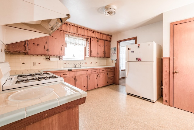 kitchen featuring premium range hood, tile countertops, sink, white refrigerator, and range