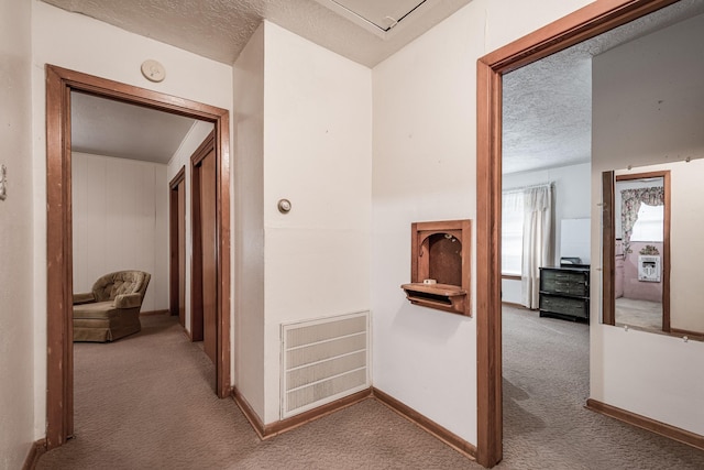 corridor with carpet and a textured ceiling