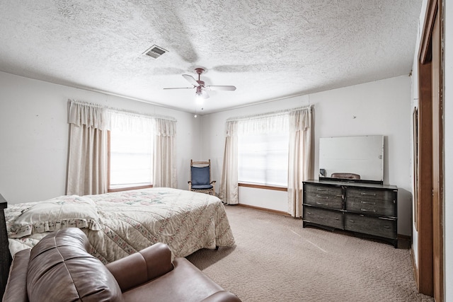 bedroom with multiple windows, a textured ceiling, light carpet, and ceiling fan