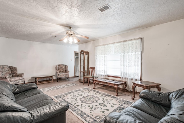 carpeted living room with ceiling fan and a textured ceiling