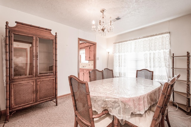 dining room featuring a healthy amount of sunlight, a textured ceiling, and a chandelier