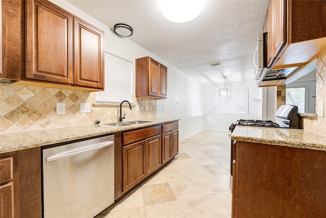 kitchen featuring sink, light stone counters, a textured ceiling, stainless steel appliances, and backsplash