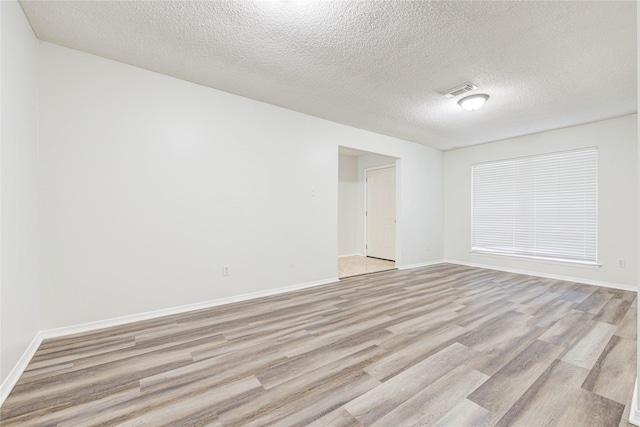 spare room with light hardwood / wood-style floors and a textured ceiling