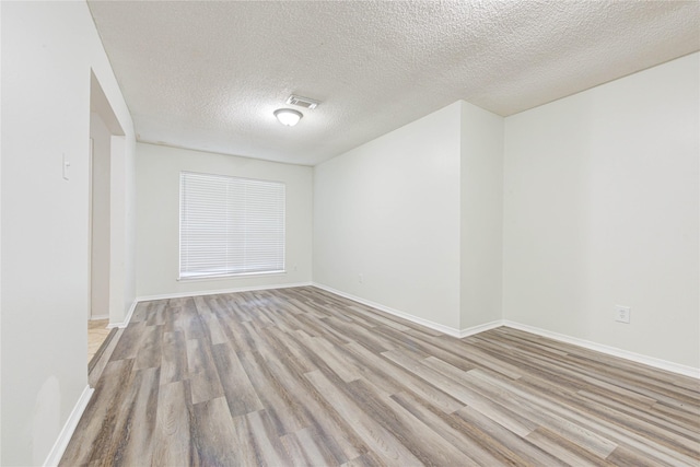 unfurnished room with light hardwood / wood-style flooring and a textured ceiling