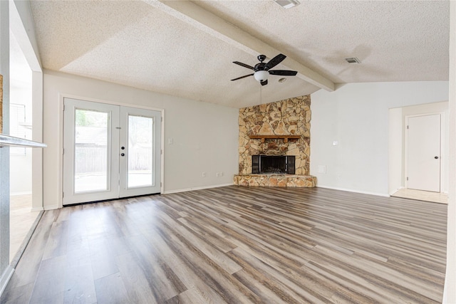 unfurnished living room with a fireplace, lofted ceiling with beams, ceiling fan, light hardwood / wood-style floors, and a textured ceiling