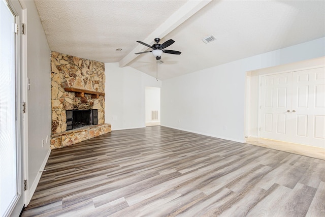 unfurnished living room with lofted ceiling with beams, a fireplace, light hardwood / wood-style floors, and a textured ceiling