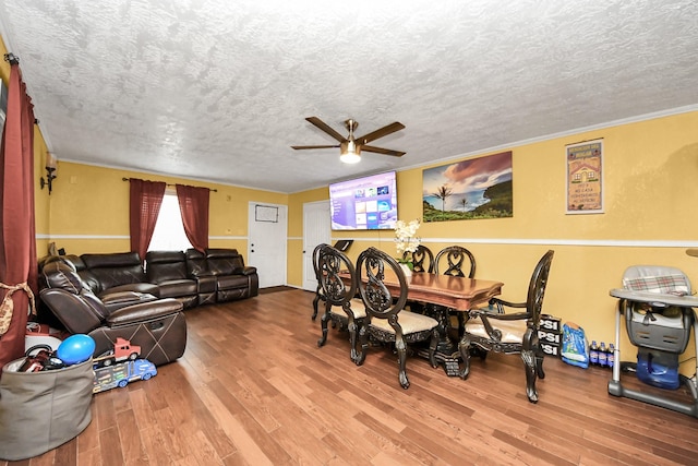 dining space with crown molding, a textured ceiling, a ceiling fan, and wood finished floors