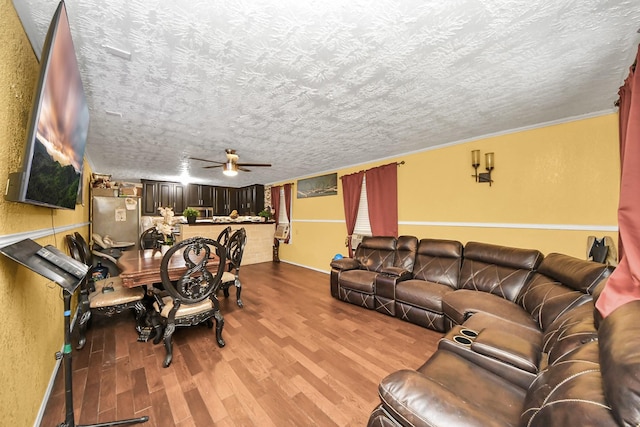 living area featuring a textured ceiling, ceiling fan, a textured wall, and light wood-style flooring