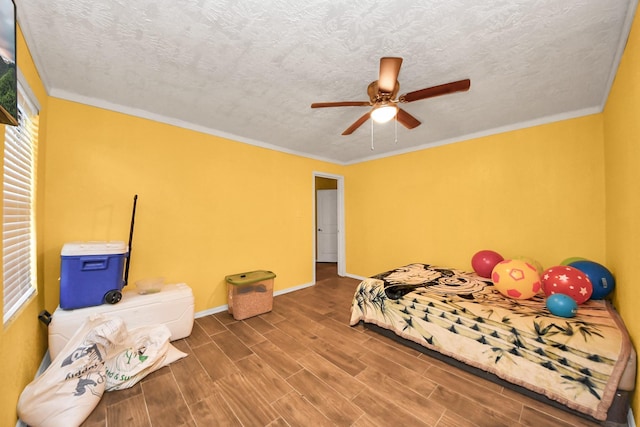 bedroom featuring wood finish floors, crown molding, a textured ceiling, and baseboards