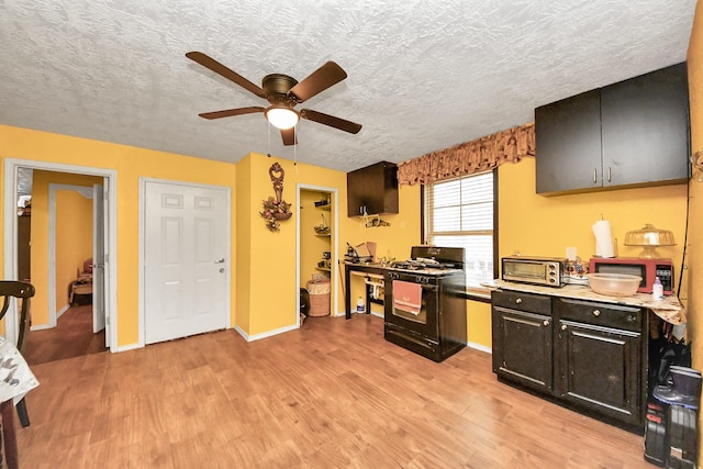 kitchen with light wood finished floors, black range with gas cooktop, light countertops, and a textured ceiling