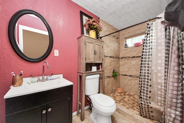 full bathroom with a textured wall, toilet, a tile shower, a textured ceiling, and vanity