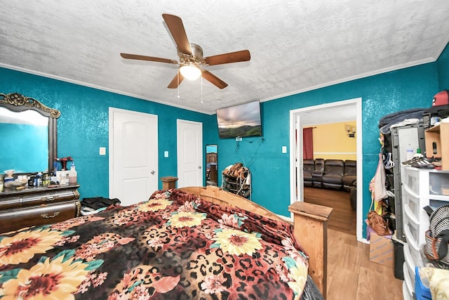 bedroom with a textured ceiling, wood finished floors, a ceiling fan, and crown molding