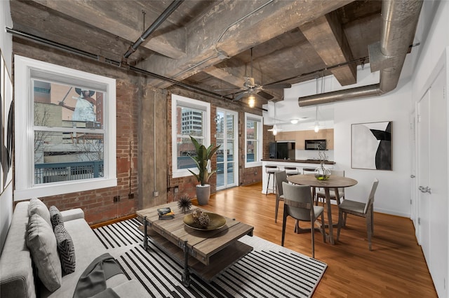 living room with brick wall, ceiling fan, and light hardwood / wood-style flooring