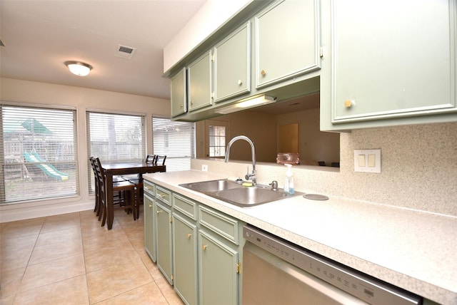 kitchen with sink, tasteful backsplash, light tile patterned floors, dishwasher, and green cabinets