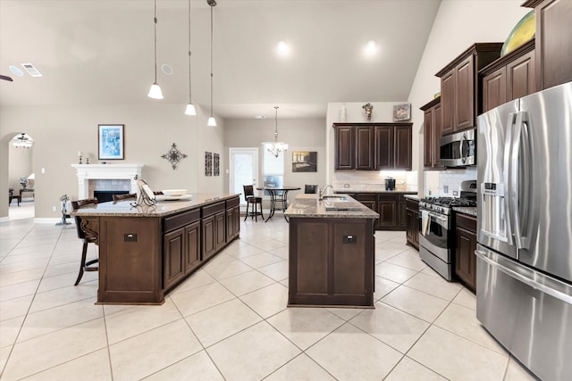 kitchen featuring hanging light fixtures, an island with sink, appliances with stainless steel finishes, and dark brown cabinets