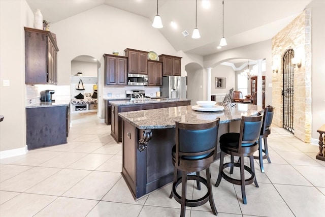 kitchen with appliances with stainless steel finishes, a large island, light tile patterned floors, and decorative light fixtures