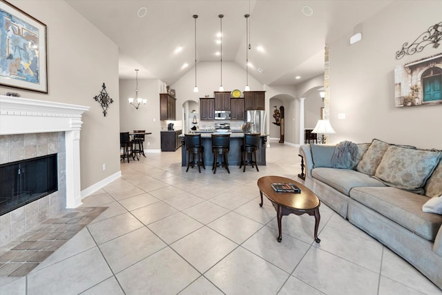 living room with high vaulted ceiling, a chandelier, a fireplace, and light tile patterned floors