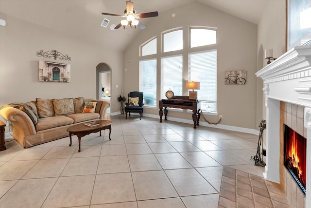 living room with a fireplace, high vaulted ceiling, ceiling fan, and light tile patterned flooring