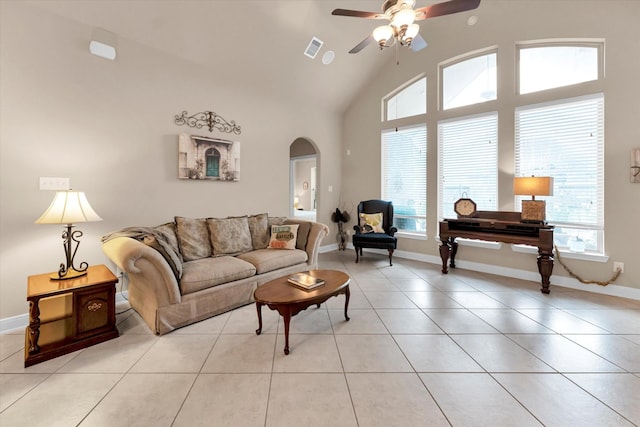 tiled living room with ceiling fan and high vaulted ceiling