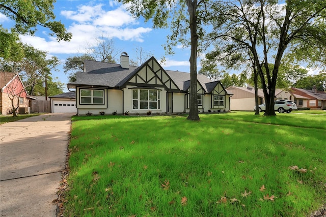 tudor home featuring a garage and a front lawn