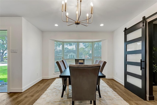 dining space featuring an inviting chandelier, hardwood / wood-style floors, and a barn door