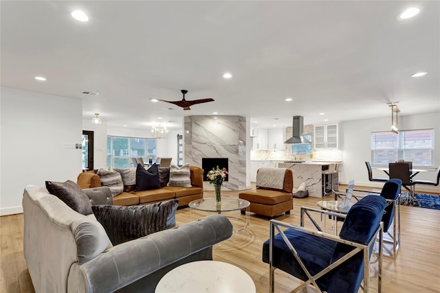 living room featuring ceiling fan, a healthy amount of sunlight, a fireplace, and light hardwood / wood-style floors