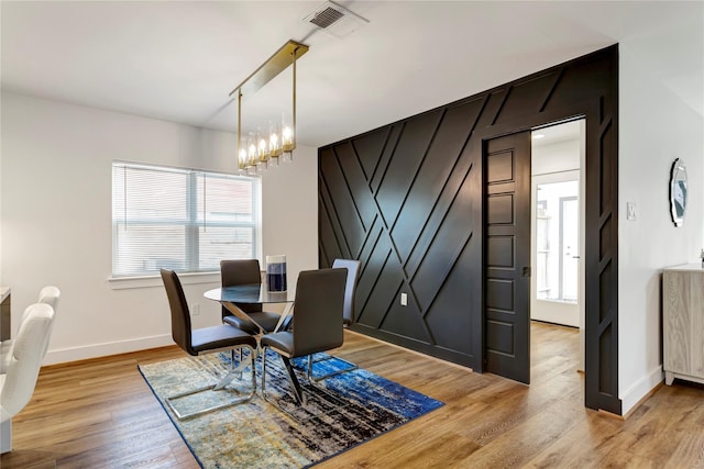 dining space featuring light hardwood / wood-style floors and a chandelier