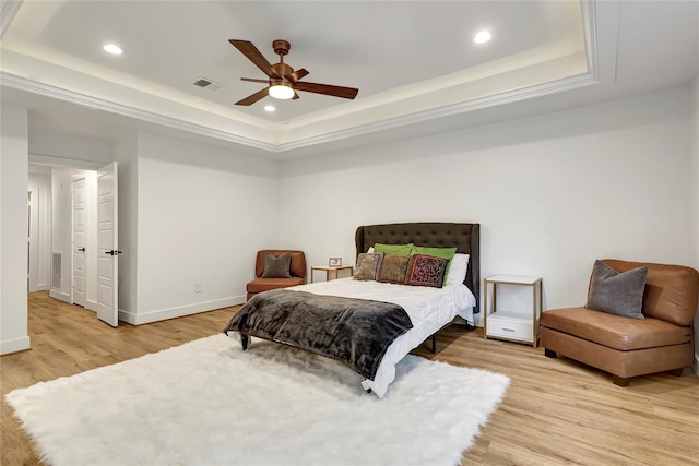 bedroom with ceiling fan, a raised ceiling, and light hardwood / wood-style floors