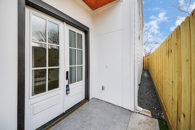 doorway to property with a patio area, fence, and stucco siding