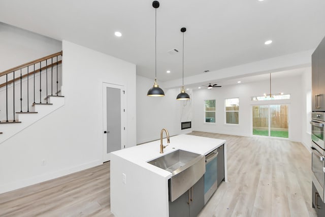 kitchen featuring open floor plan, appliances with stainless steel finishes, a kitchen island with sink, and pendant lighting